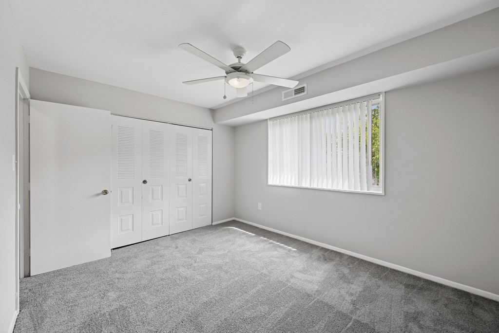 A room with a ceiling fan and a window with blinds.