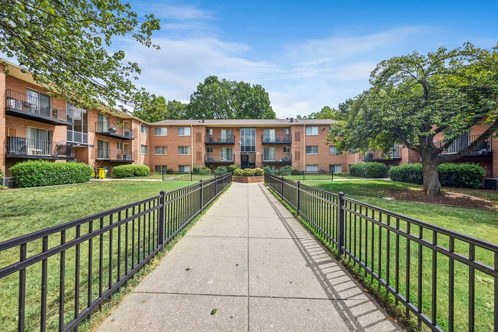 A long concrete walkway leads to apartment buildings.