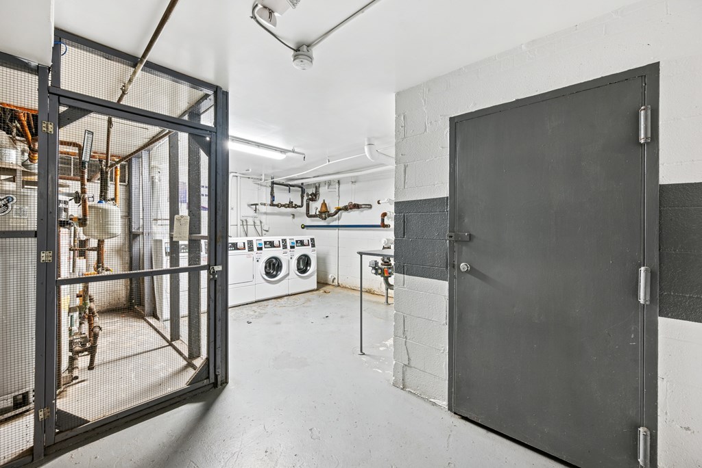 A large black door is open to a room with a washing machine and other appliances.