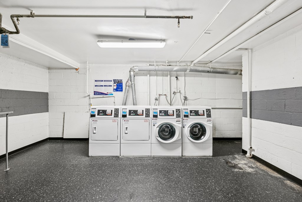 A laundry room with two washing machines and a pipe running along the wall.