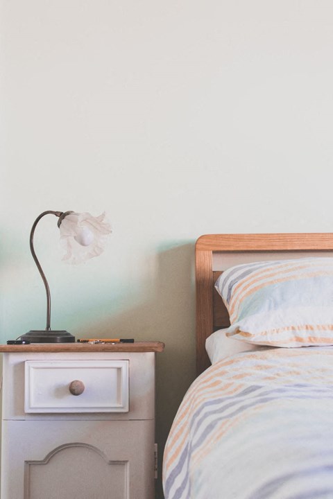 a bedroom with a bed and a nightstand with a lamp