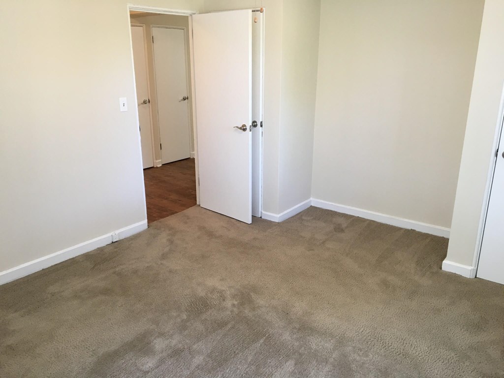 A room with a carpeted floor and a white door.at Greenbelt Properties, Greenbelt, MD