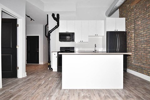 A kitchen with white cabinets and a black fridge.