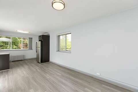 A spacious room with a black fridge and wooden flooring.