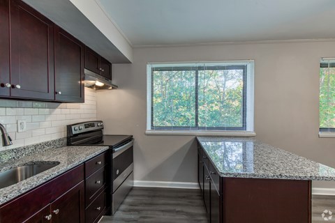 A kitchen with dark wood cabinets and a granite countertop.