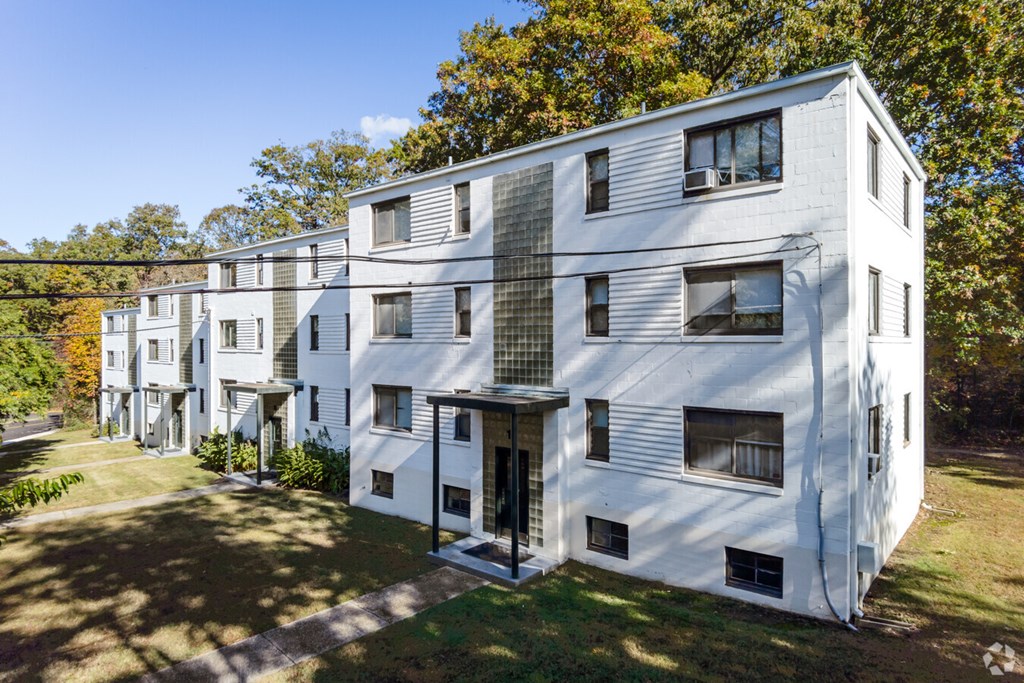 A white apartment building with a green lawn in front.at Greenbelt Properties, Greenbelt, MD