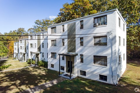 A white apartment building with a green lawn in front.