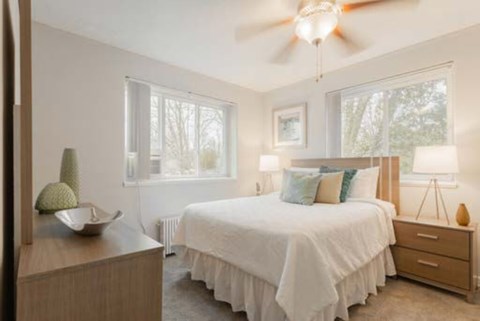 A bedroom with a bed, nightstand, and a ceiling fan.