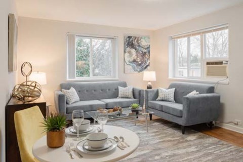 A modern living room with a grey couch, a white coffee table, and a yellow chair.