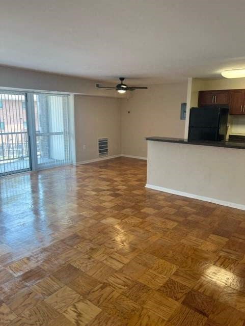 an empty living room with a sliding glass door and a ceiling fan