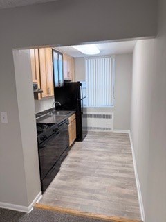 A black refrigerator is in a kitchen with white walls.