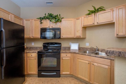 A kitchen with wooden cabinets and a black refrigerator.