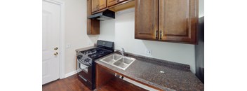 A kitchen with a stove, sink and cabinets.