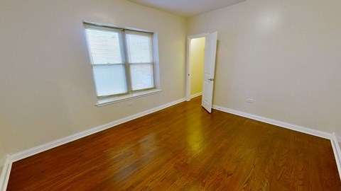 a bedroom with wood floors and a window and a door