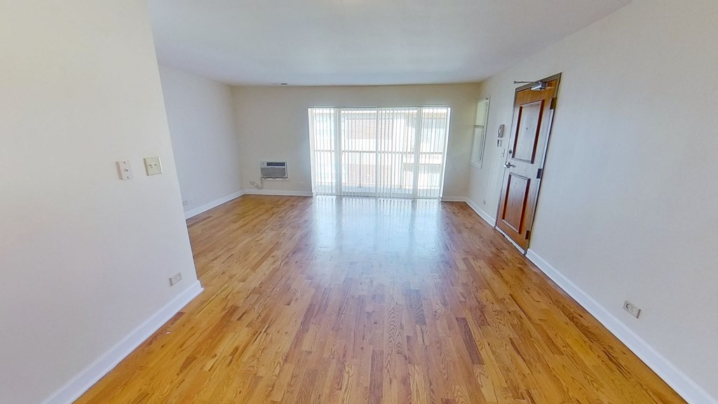 an empty living room with wood flooring and a window