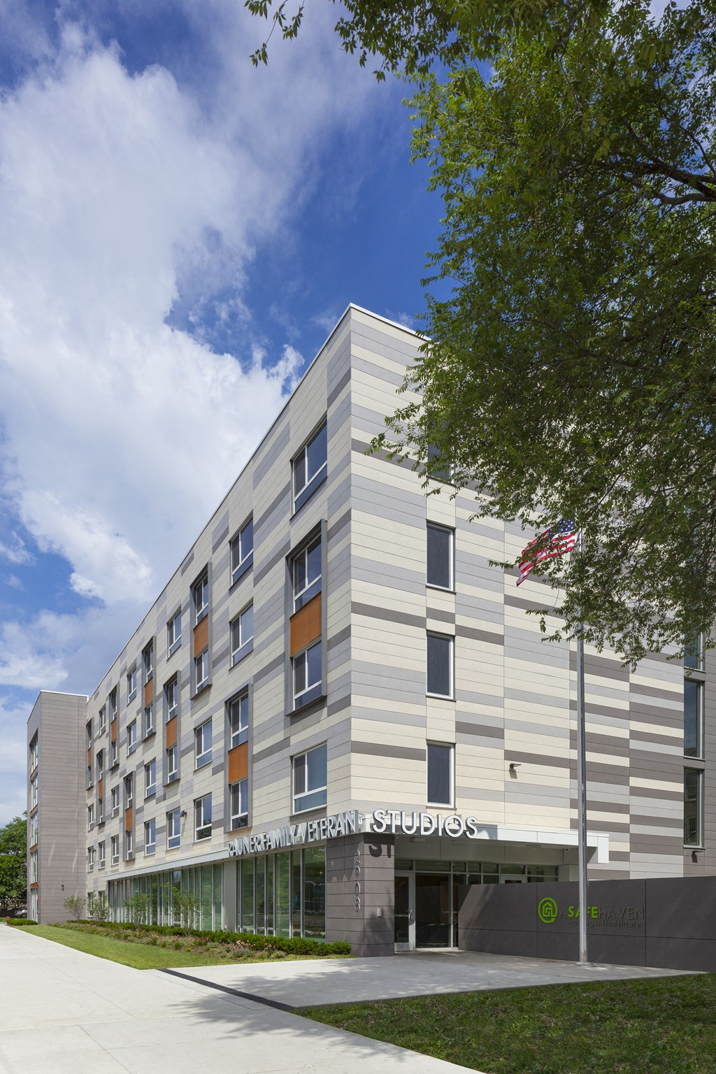 a building with a sidewalk and a tree in front of it