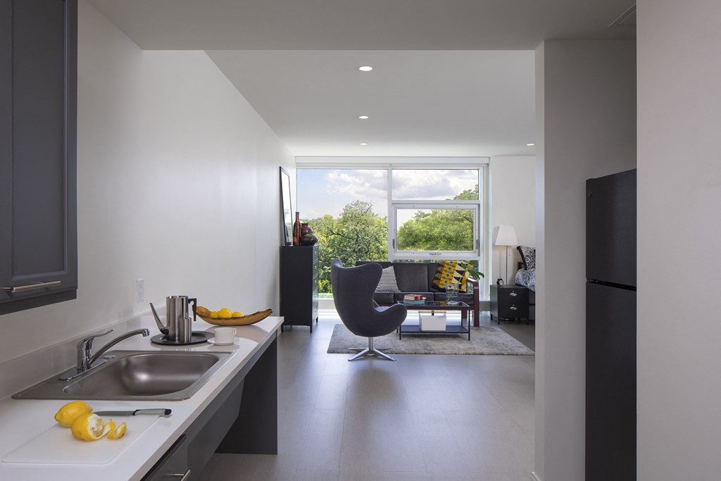 a kitchen with a sink and a counter and a living room with a large window