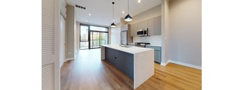 A modern kitchen with a white island and dark wood floors.