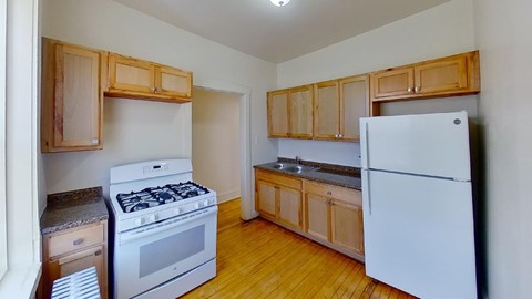 A kitchen with a white fridge, stove and wooden cabinets.