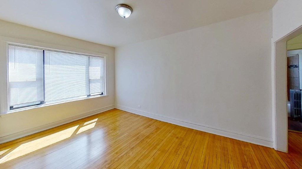 an empty living room with a large window and wood floors