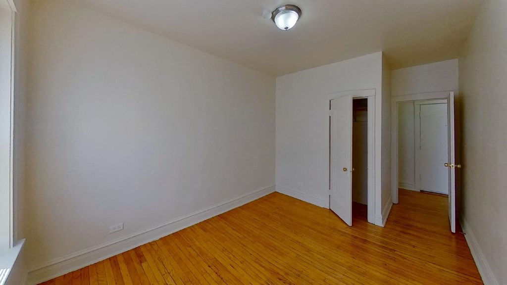a bedroom with a hard wood floor and white walls