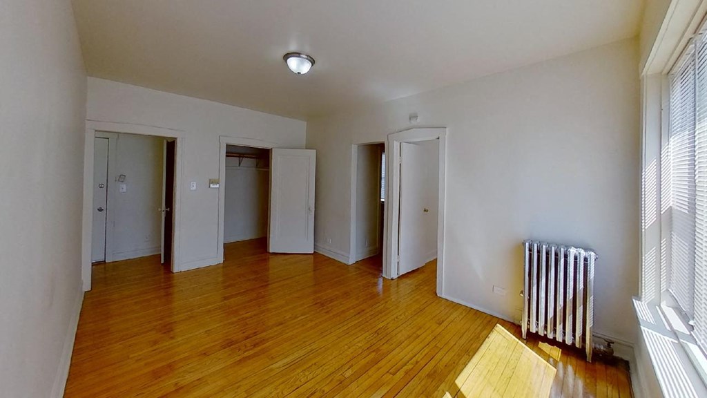 a living room with wood floors and white walls     and three doors