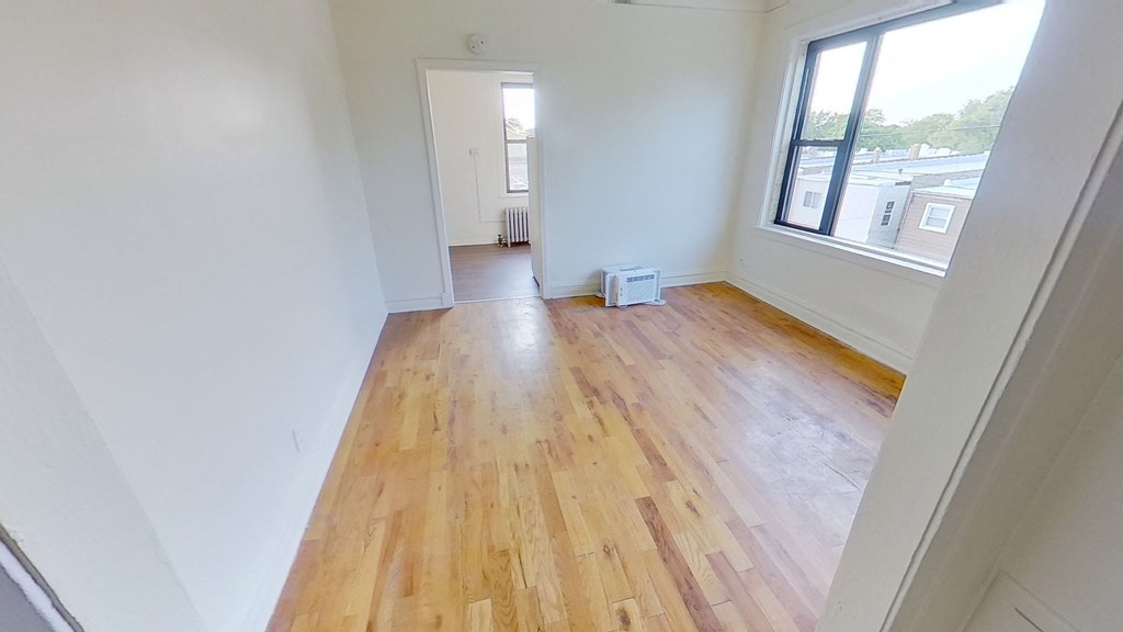 an empty living room with wooden floors and a large window