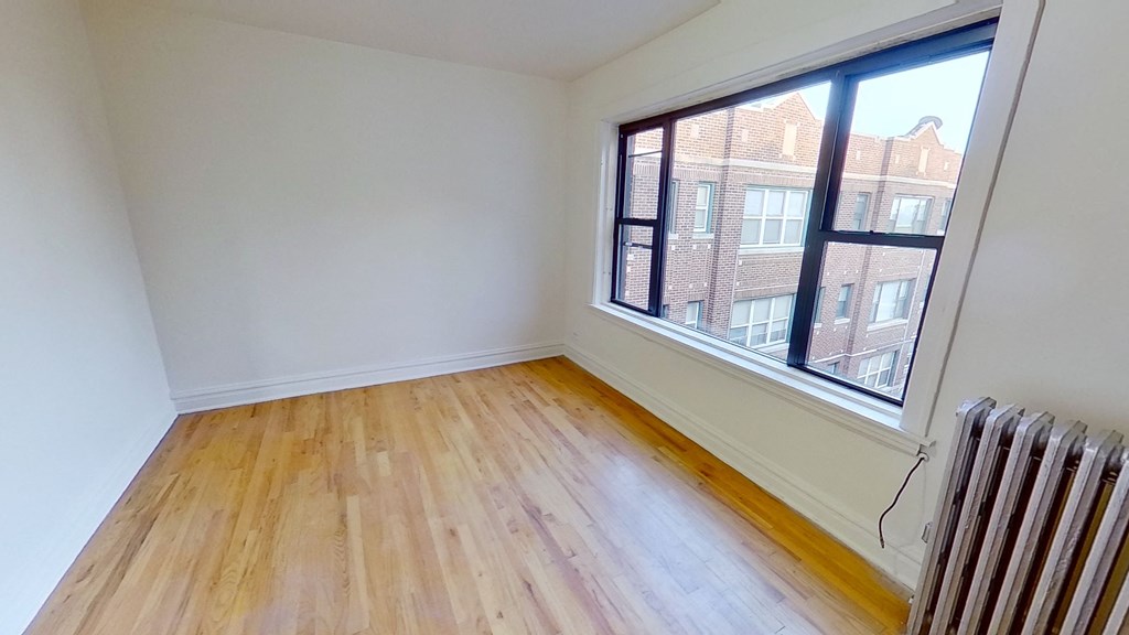 an empty room with wooden floors and a large window