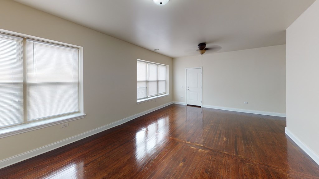 an empty living room with hardwood floors and three windows