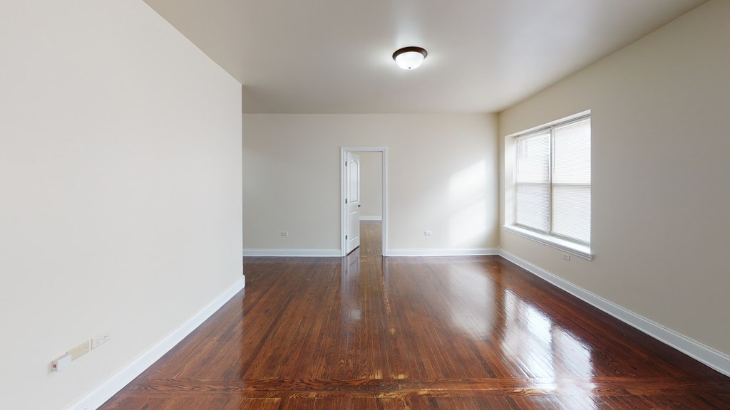 an empty living room with wood floors and a window