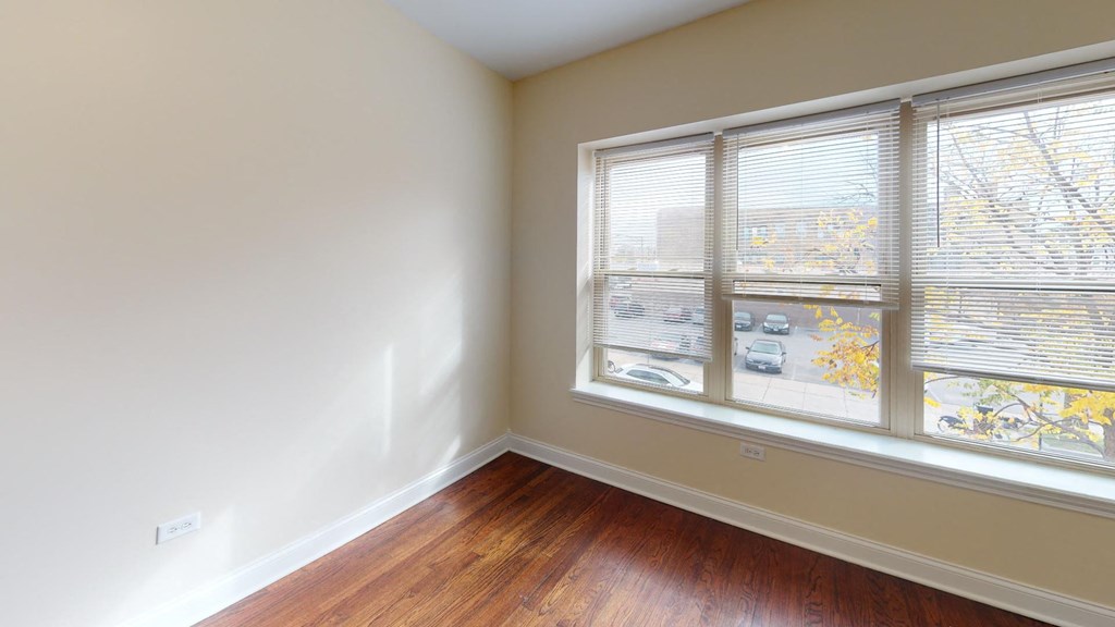 a bedroom with a large window and wood floors