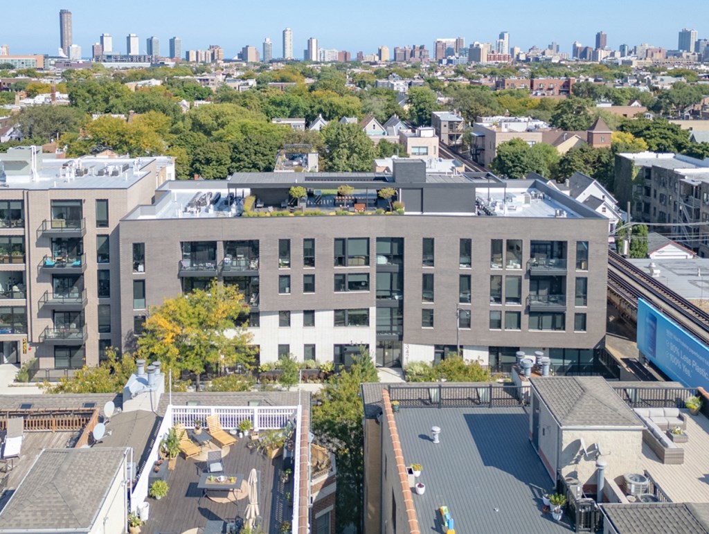 an aerial view of a building with a green roof and a city in the background
