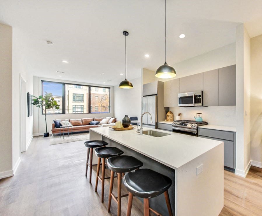 an open kitchen and living room with an island and bar stools