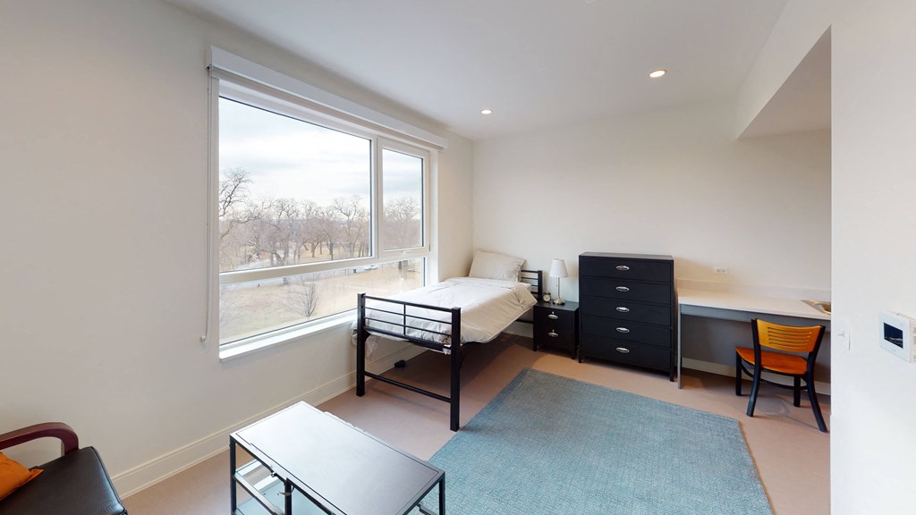 a bedroom with a bed and a desk and a window