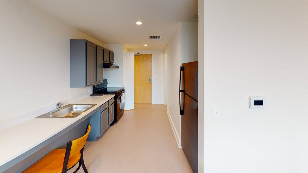 a long kitchen with a sink and a refrigerator in a apartment