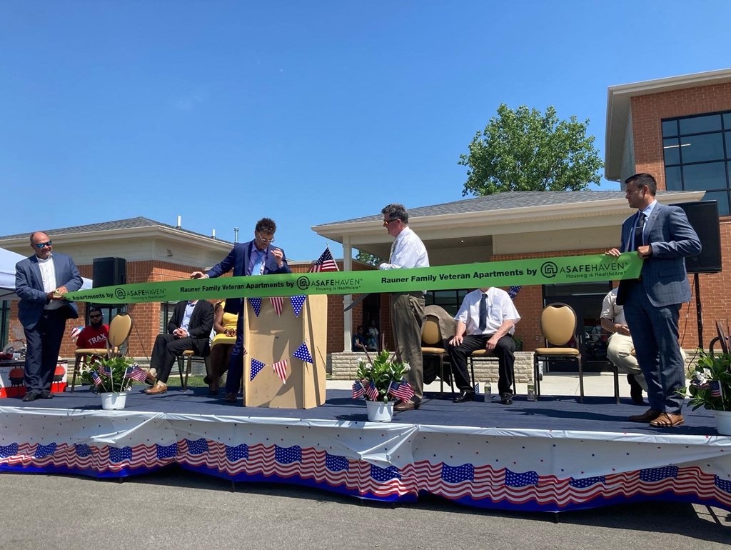 a group of people cutting a ribbon on a table