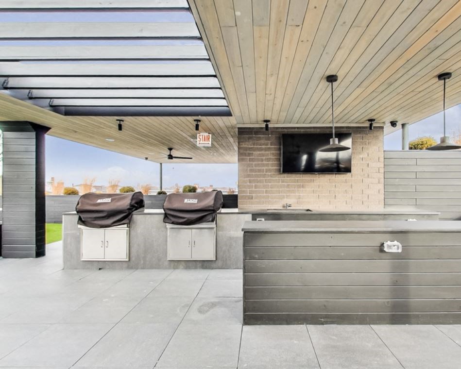 the patio has a bar with two chairs and a tv