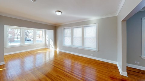 an empty living room with a hard wood floor and three windows