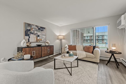 A modern living room with a white sofa, a coffee table, and a large painting on the wall.