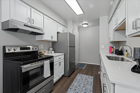 A modern kitchen with a black stove top oven and white cabinets.