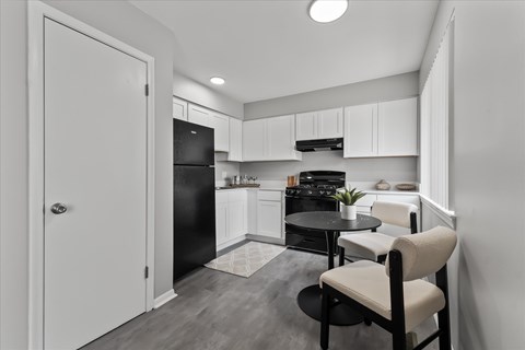 A black and white photo of a kitchen with a table and chairs.