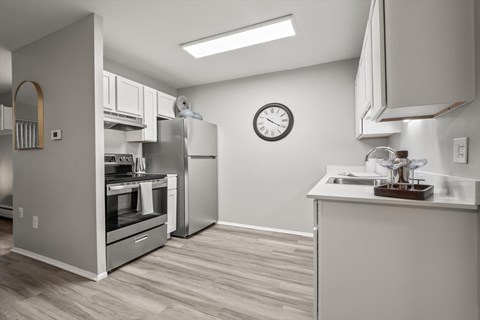 A modern kitchen with a stainless steel refrigerator and a wooden floor.