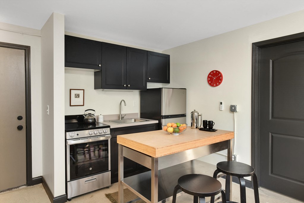 a kitchen with black cabinets and a table with two stools