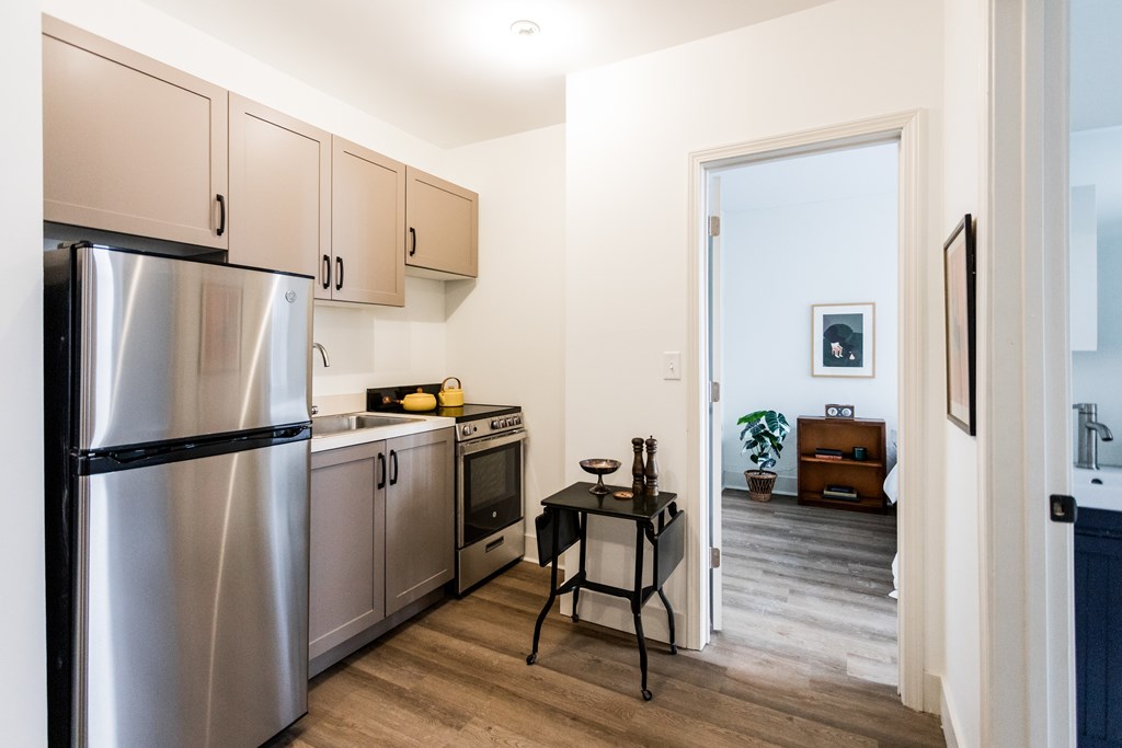 A kitchen with a refrigerator, oven, and a table.