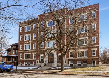 a red brick apartment building with a tree in front of it