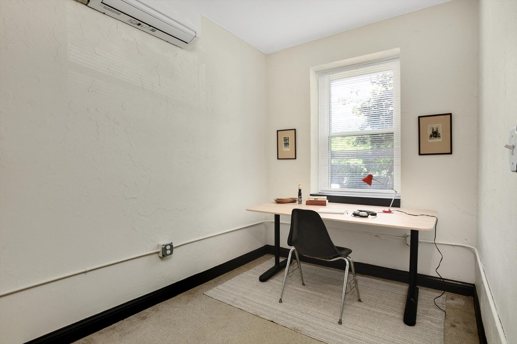 a desk in a room with a white wall and a window