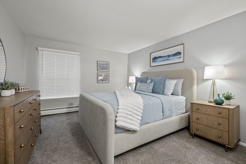 A bedroom with a bed, nightstand, and dresser.