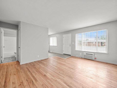 the living room and dining room of a house with wood floors and a large window