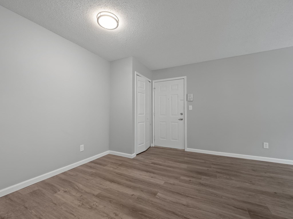 an empty living room with wood flooring and a white door