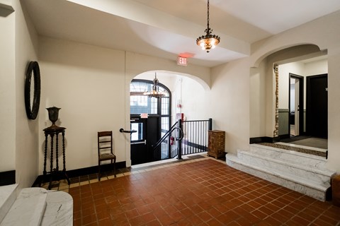 A hallway with a black door and a white wall.